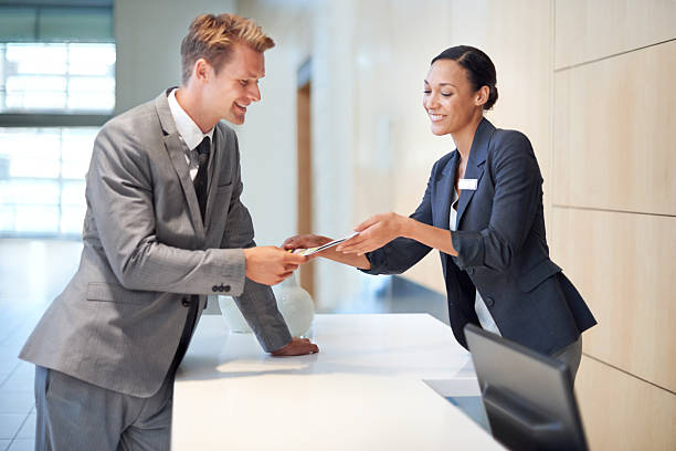 Charge it to my current account A handsome young man handing over a credit card to a woman concierge photos stock pictures, royalty-free photos & images
