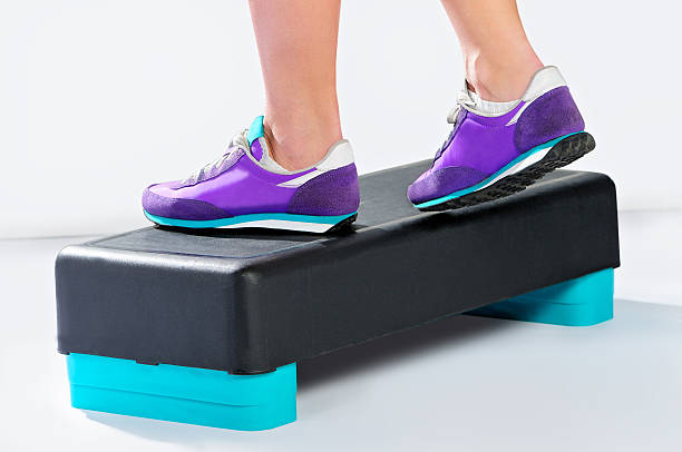 istock Female feet in violet sneakers do exercise on aerobic step. 470749726