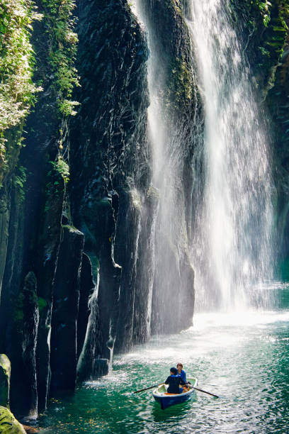 Takachiho, Japan - September 28, 2014: tourists visting the Takachiho Gorge using small boats. In the background the famous Manai Waterfall.