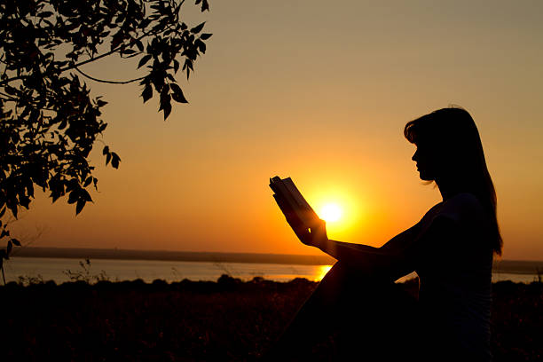 istock silhouette of a girl reading at sunset 470750161