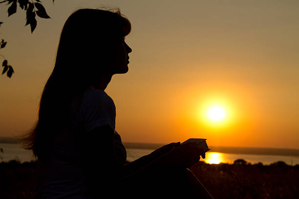 istock silhouette of a girl reading at sunset 470750171