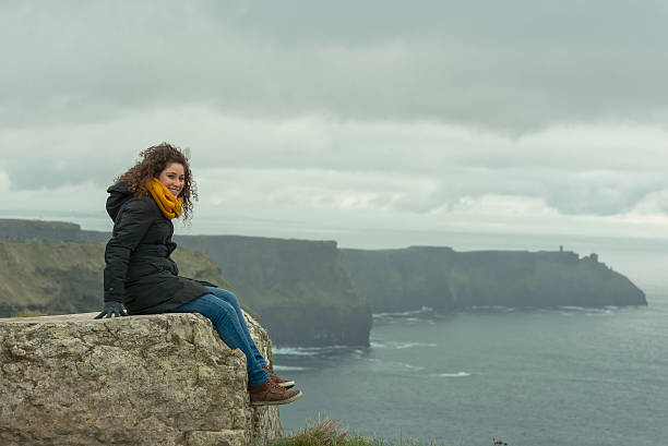 beautiful girl on a trip to the cliff of moher beautiful girl on a trip to the cliff of moher on a winter day. the girl has beautiful curly hair cliffs of moher stock pictures, royalty-free photos & images