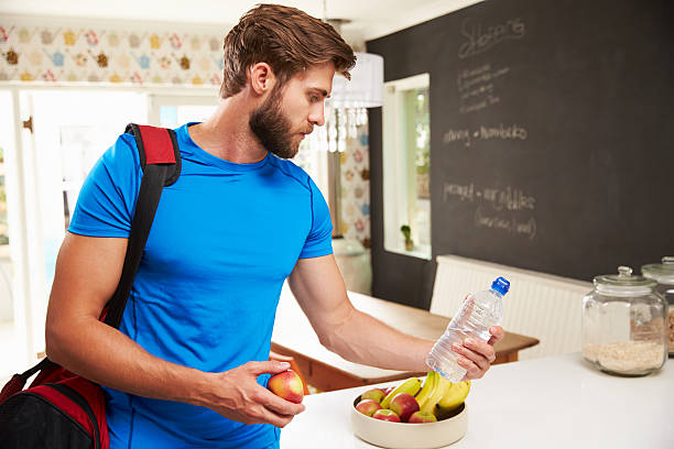 istock Man Wearing Gym Clothing Choosing Fruit From Bowl 470754708
