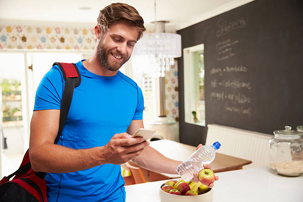 istock Man wearing gym clothes smiling and looking at a cell phone 470754782