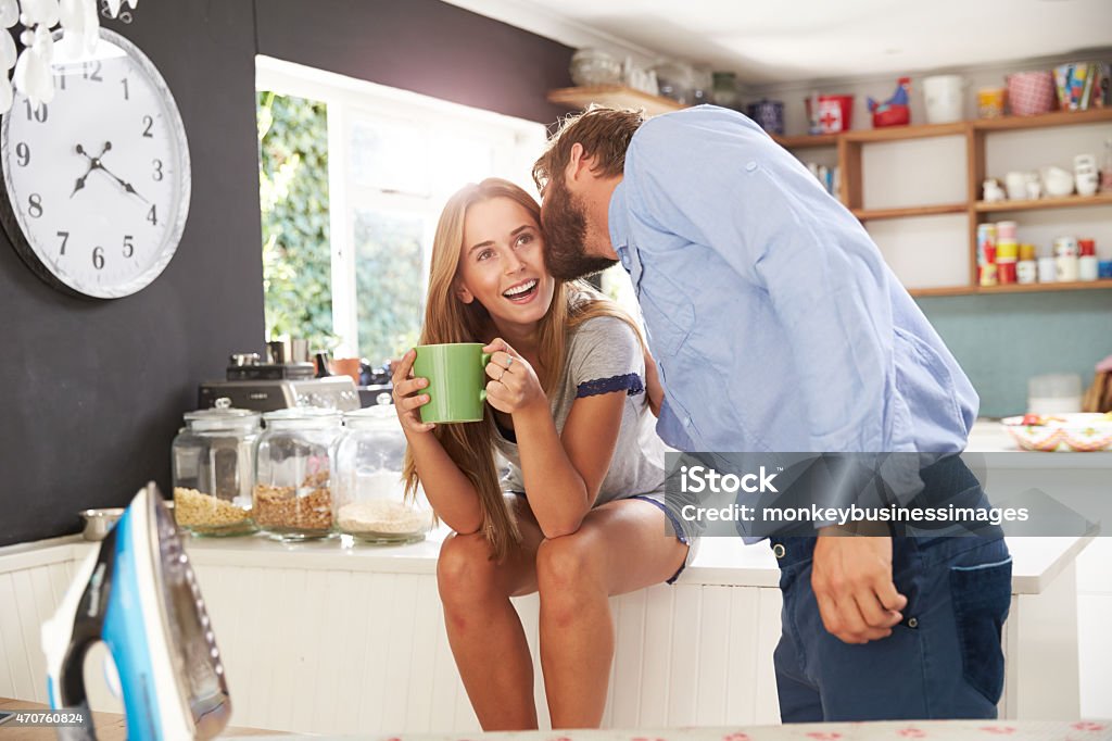 Man Ready To Leave For Work Kisses Woman In Kitchen Man Getting Ready To Leave For Work Kisses Woman In Kitchen, Smiling 20-29 Years Stock Photo