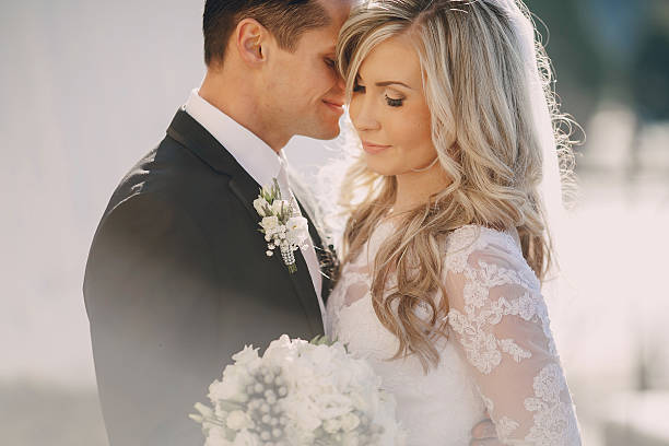Bride and groom embracing on the wedding day under the sun