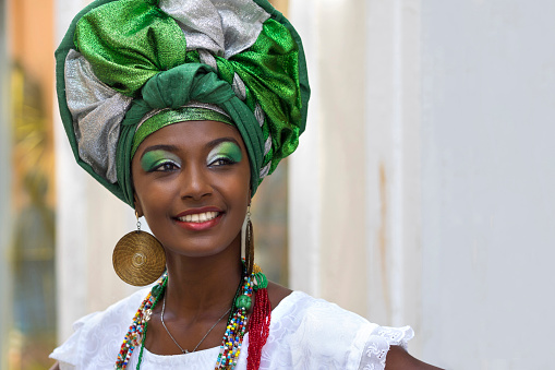 Brazilian woman of African descent, smiling, dressed in traditional Baiana attire in Pelourinho, Salvador, Bahia, Brazil.