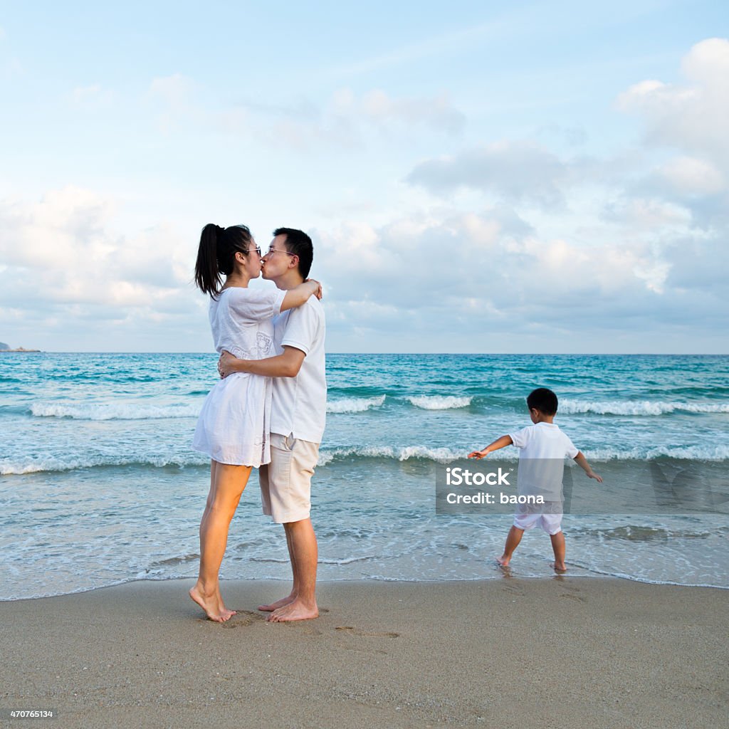 Kiss on the beach A couple kissing on the beach, and their son playing by himself. 2015 Stock Photo