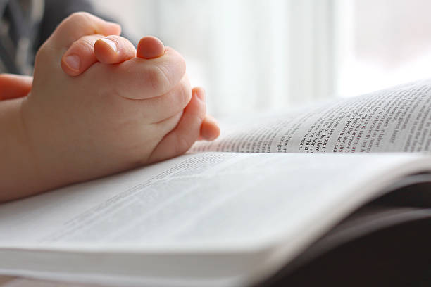 niño de manos de rezar sobre biblia sagrada - christ child fotografías e imágenes de stock