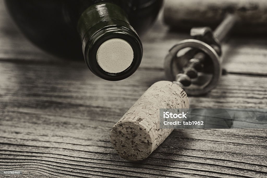 Vintage bottle of wine ready to open on aged wood Close up shot of top of wine bottle cork with antique opener in background in vintage style. Layout in horizontal format. 2015 Stock Photo