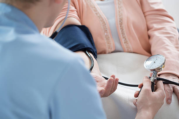 Male nurse measuring blood pressure Male nurse measuring blood pressure of ill woman nurse smock stock pictures, royalty-free photos & images