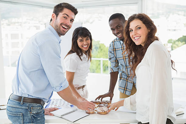 istock Smiling coworkers taking doughnut at desk 470783990