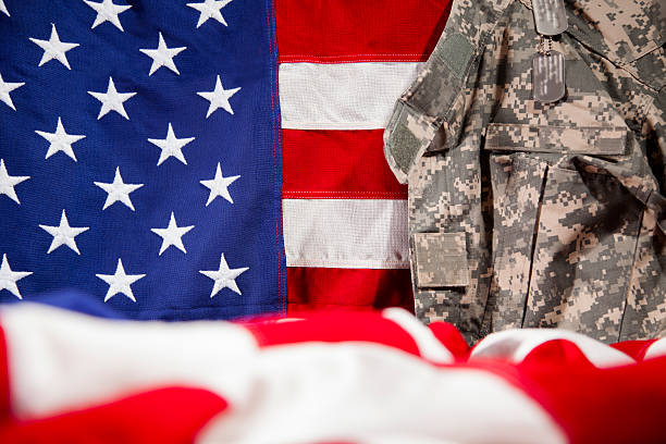 istock U.S.A. military uniform hangs beside American flags. Respect, patriotism. 470784336