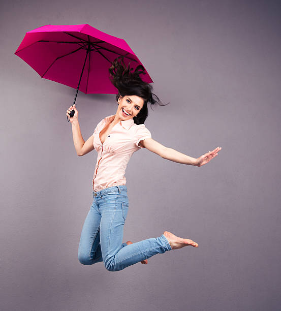 istock Happy young woman jumping with umbrella 470784530