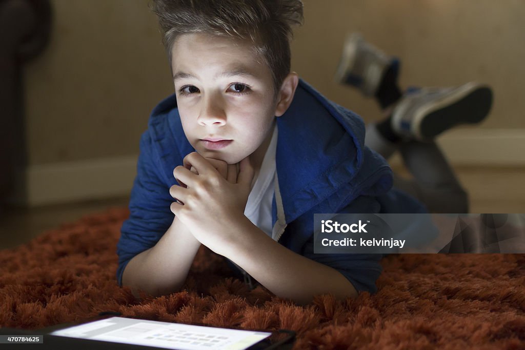Petit garçon à l'aide d'une tablette numérique sur le sol - Photo de Être étendu libre de droits