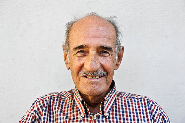 Close up horizontal portrait serious older man against white background staring