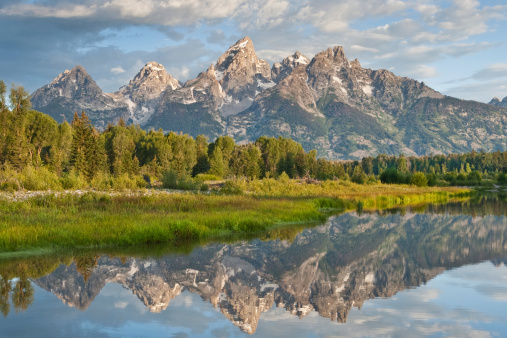 The Snake River flows quietly through the Jackson Hole Valley. In many places the water is so calm and glassy that a perfect reflection of the Teton Range is often seen. This picture of the Tetons at first light was taken from Schwabacher Landing, a very popular place for photographers. Schwabacher Landing is in Grand Teton National Park near Jackson, Wyoming, USA.