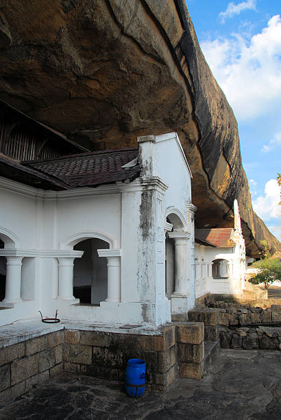 Dambulla, Matale District, Central Province, Sri Lanka: frontage of Golden Temple of Dambulla under a giant rock slab - Dambulla cave temple - UNESCO World Heritage Site - photo by M.Torres