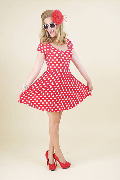Pin-Up Girl in Polka Dot Dress A Pin-Up Girl Model in a red Polka Dot Dress, with sunglasses, posing in front of a vanilla background. 40s pin up girls stock pictures, royalty-free photos & images