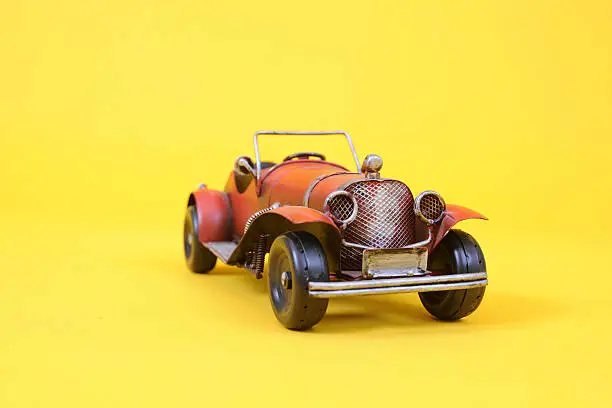 A red Toy car roadster on a Yellow Backdrop