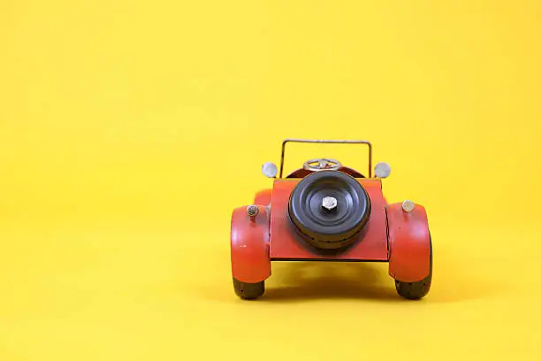 A red Toy car roadster on a Yellow Backdrop