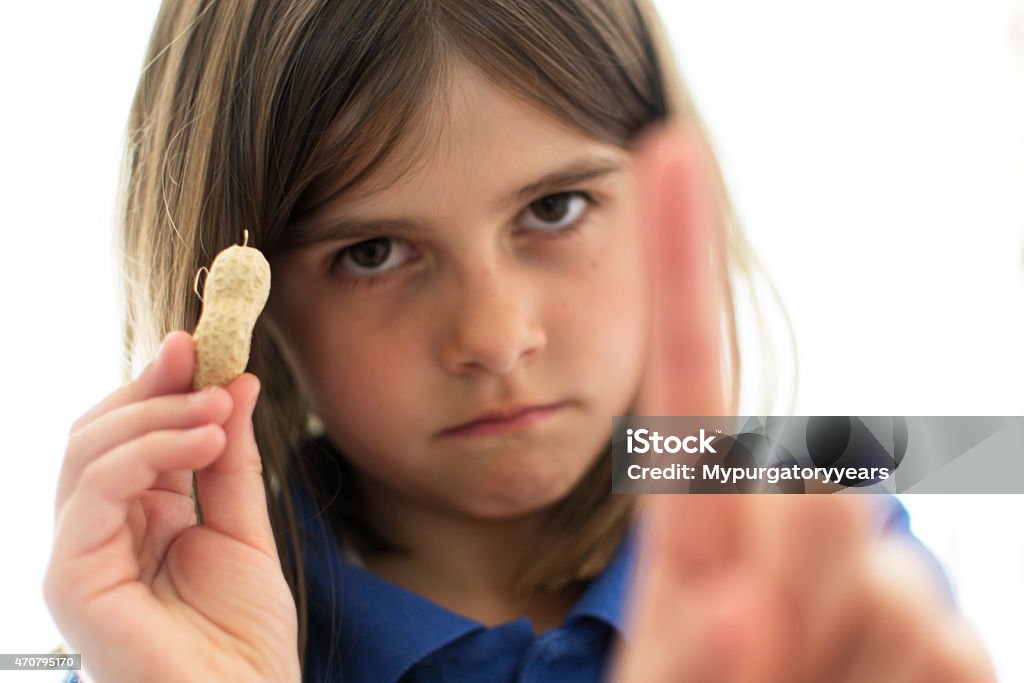 Beware contains nuts A young girl holding a peanut and wagging her finger as a warning to people with nut allergies. Allergy Stock Photo