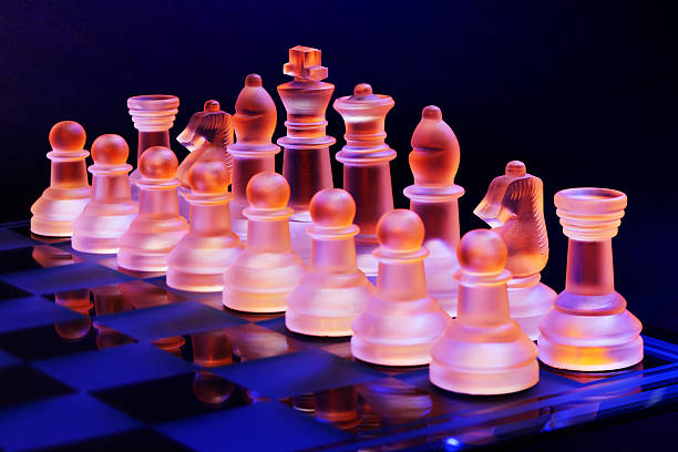 scacchiera con scacchi di vetro illuminato da luce blu e arancione - armed forces black yellow chess pawn foto e immagini stock