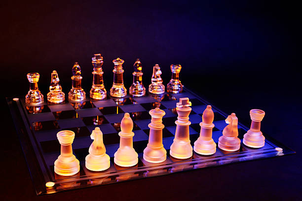 scacchiera con scacchi di vetro illuminato da luce blu e arancione - armed forces black yellow chess pawn foto e immagini stock