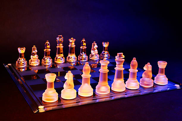 scacchiera con scacchi di vetro illuminato da luce blu e arancione - armed forces black yellow chess pawn foto e immagini stock