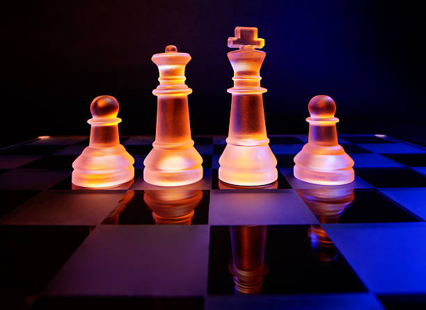 scacchiera con scacchi di vetro illuminato da luce blu e arancione - armed forces black yellow chess pawn foto e immagini stock