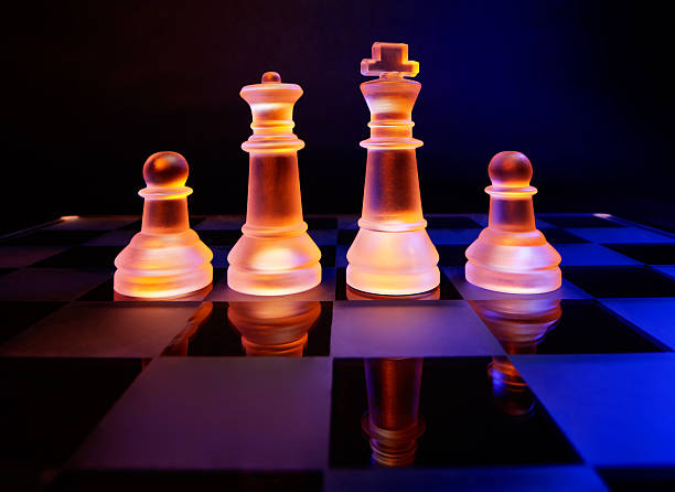 istock Glass chess on chessboard lit by blue and orange light 470796767