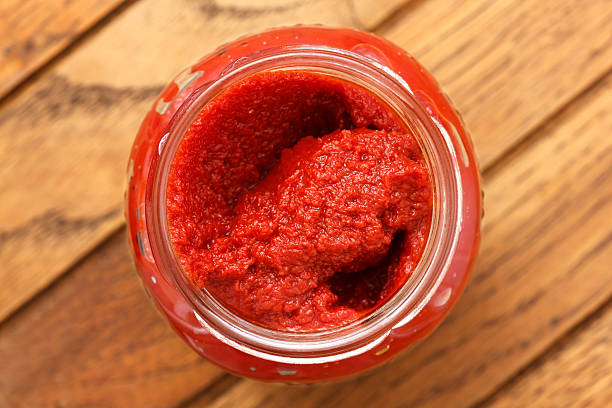 istock Open glass jar of tomato paste. On rustic wood surface. 470797648