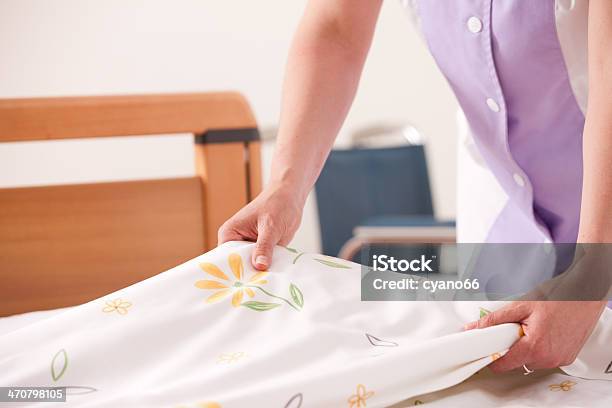 Woman Dressed In Lavender Arranging Sheets And Making Bed Stock Photo - Download Image Now