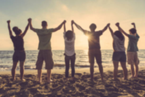 istock Group of people with raised arms at seaside, blurred background 470800278