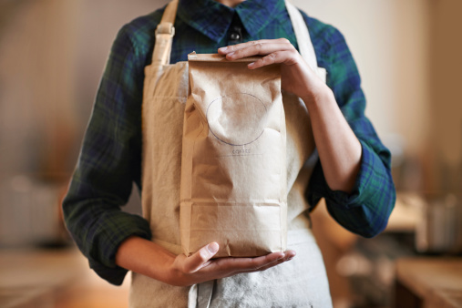 Cropped shot of a woman holding a bag while wearing an apron