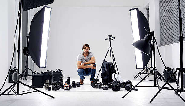 Ready to shoot! A professional photographer in his studio surrounded by equipment camera photographic equipment stock pictures, royalty-free photos & images