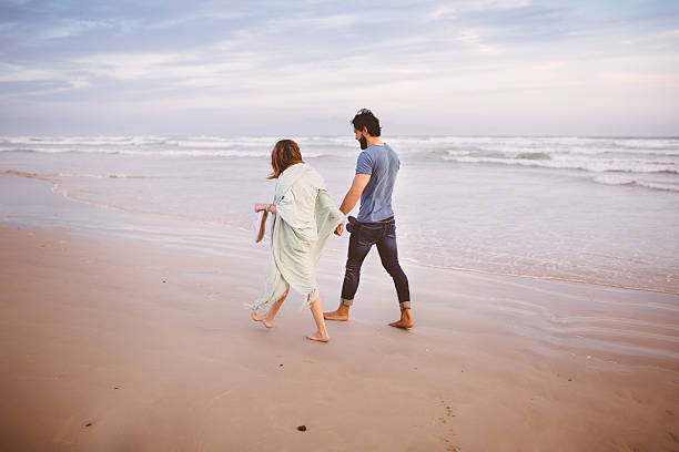istock Couple holding hands while walking along a beach together 470808768