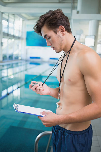 istock Swimming instructor holding stopwatch and clipboard by the pool 470811506