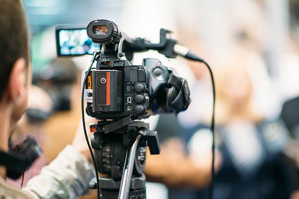 Public Relations Television camera recording publicity event. Camera in focus, operator and event blurred interview event photos stock pictures, royalty-free photos & images
