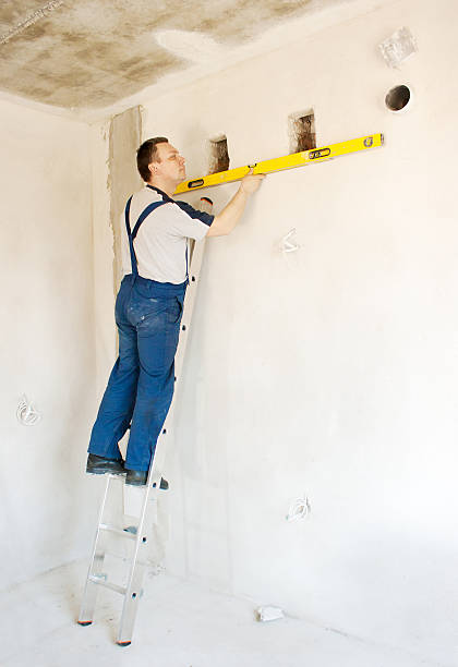istock man worker checks the wall with a level 470817670