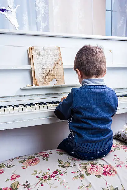 Little boy sitting at a white piano