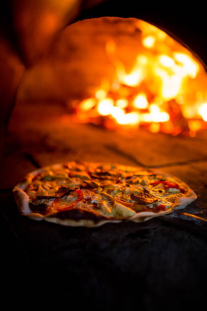 istock Vegetarian pizza being placed inside a wood fire oven 470818720
