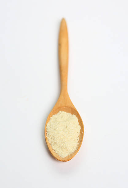 istock Powdered milk in wooden spoon over white background 470819058