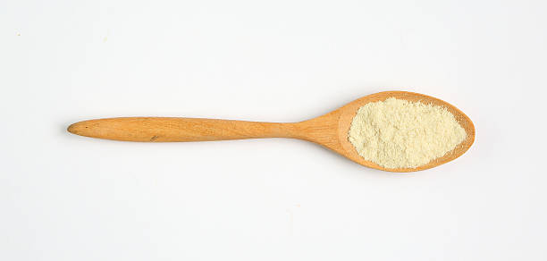 istock Powdered milk in wooden spoon over white background 470819634