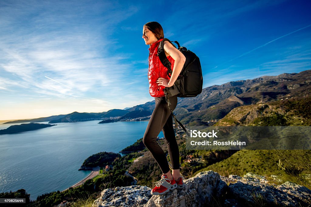 Sports woman on the top of mountain Sports woman in red vest with backpack standing on the top of mountain on the sunset. 2015 Stock Photo