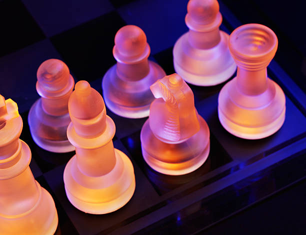 glas schach auf der schachbrett-hell blau und orange licht - armed forces black yellow chess pawn stock-fotos und bilder