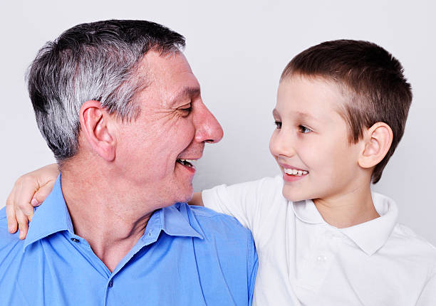 felice nonno e nipote maschio - whispering grandparent child grandfather foto e immagini stock