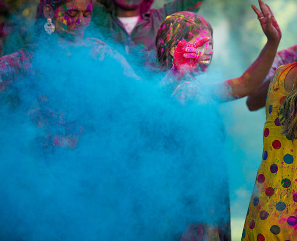 Young woman dancing around blue powder while celebrating the Indian Holi Day