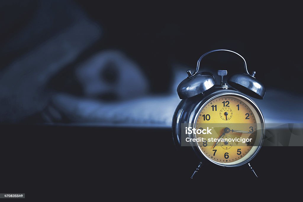 Joven durmiendo en la cama - Foto de stock de Despertador libre de derechos
