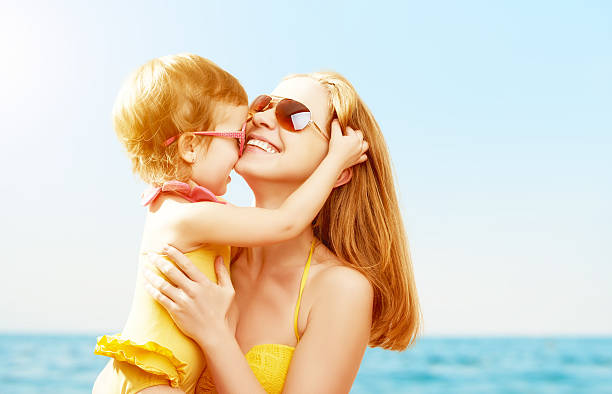 famiglia felice sulla spiaggia. figlia bacia la madre - hat toddler little girls pink foto e immagini stock